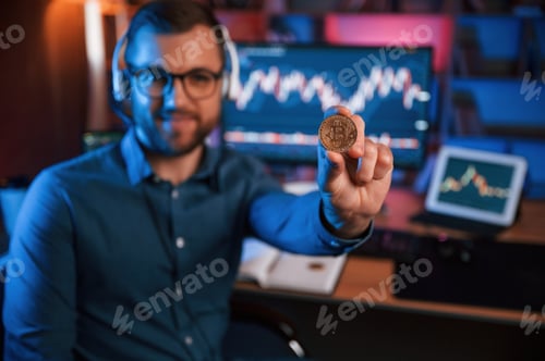 Preview: Holding bitcoin. Stock trader is working by pc indoors. Conception of exchange and money