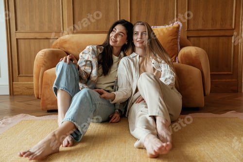Preview: Front view, sitting. Two happy young female best friends are indoors