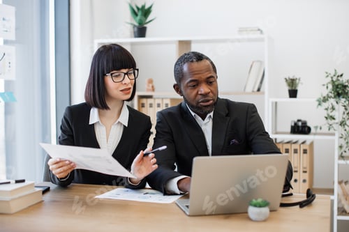 Preview: Businesswoman and coworker editing report on laptop