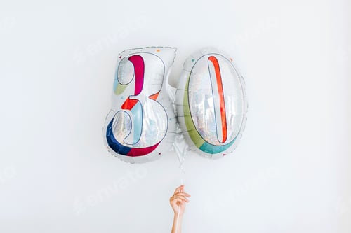 Vista previa: Studio shot of hand holding balloon in shape of number 30