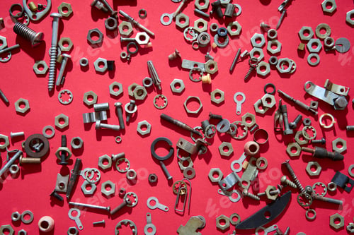 Preview: Metal nuts and bolts on red background