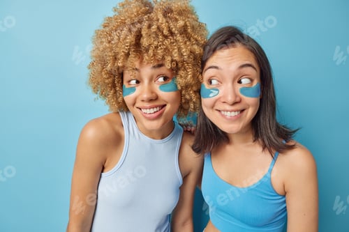 Preview: Horizontal shot of mixed race women apply beauty patches under eyes to reduce puffiness undergo skin