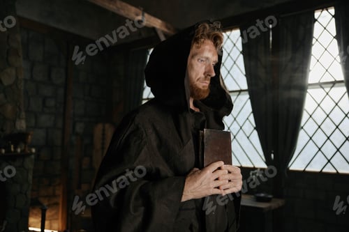 Preview: Medieval priest holding closed bible book and rosary beads in hands closeup