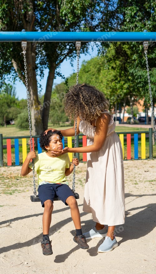 Preview: Mother putting sunscreen on her 8 year old son's face. Latin mother and son on the swings