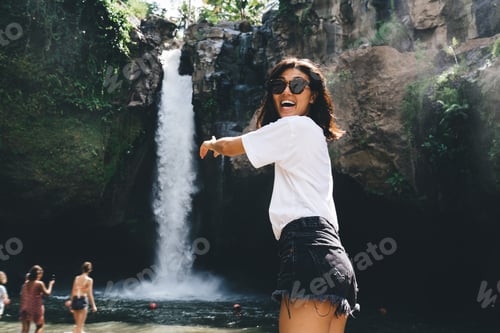 Preview: Excited tourist standing next to streaming waterfall