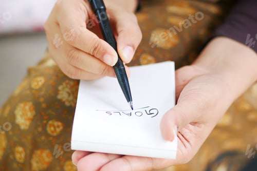 Preview: women hand writing goals on a notepad