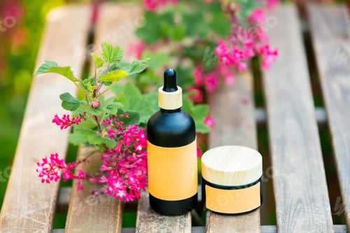 Preview: Cosmetic bottle and jar on wooden table in blooming tree spring garden