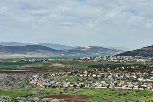 Preview: A closer aerial view of a picturesque town with red rooftops, nestled in a lush valley