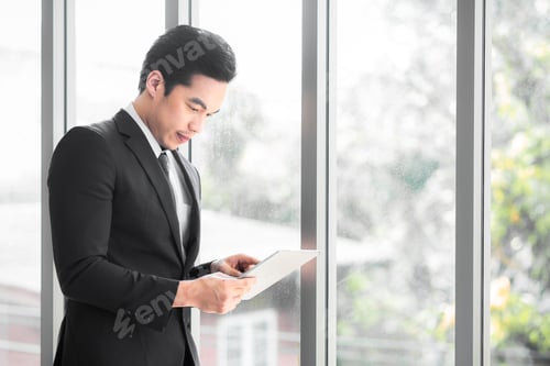 Preview: Businessman standing contemplating while use tablet