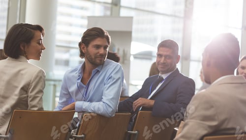 Preview: Rear view of diverse business people interacting with each other during seminar in office building