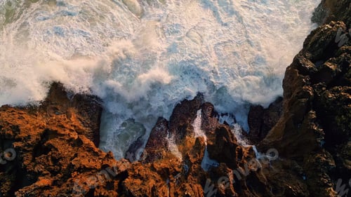 Preview: Rough water breaking coast cliffs closeup. Top view foamy sea splashing rocks