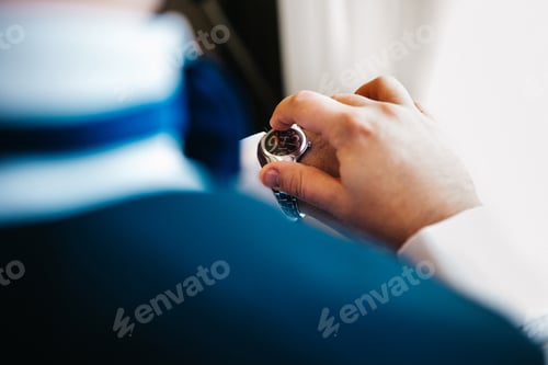 Preview: the groom in a blue suit looks at the watch worn on his left hand