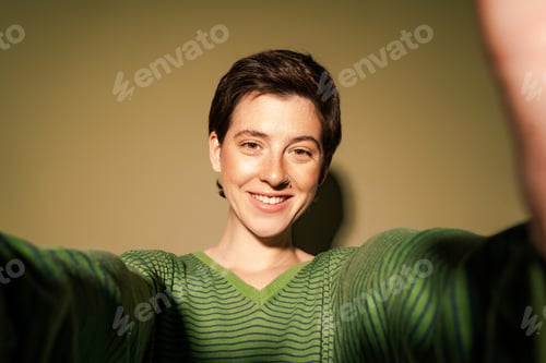 Preview: joyful and stylish woman with outstretched hands smiling at camera on green background