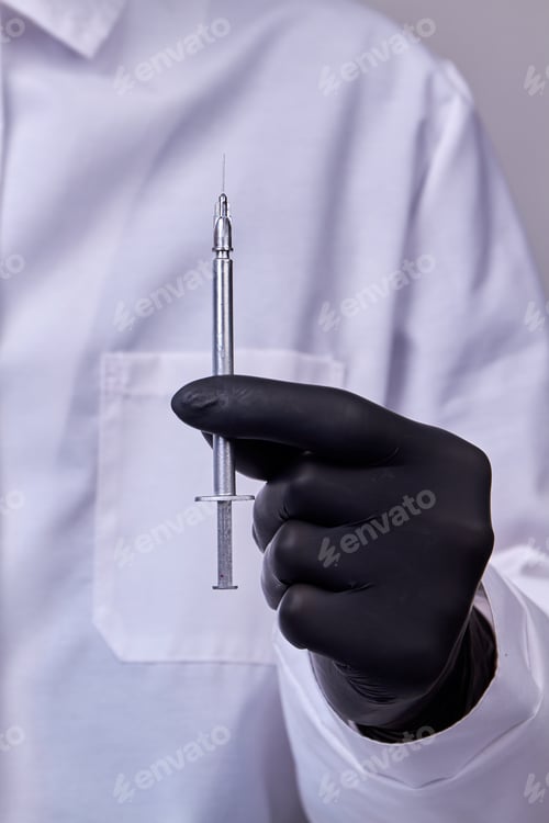 Preview: Surgeon hand in black glove holding cosmetic syringe.