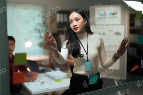 Preview: Woman presenting ideas on glass board at business meeting