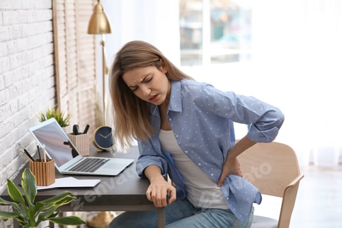 Preview: Young woman suffering from back pain in office