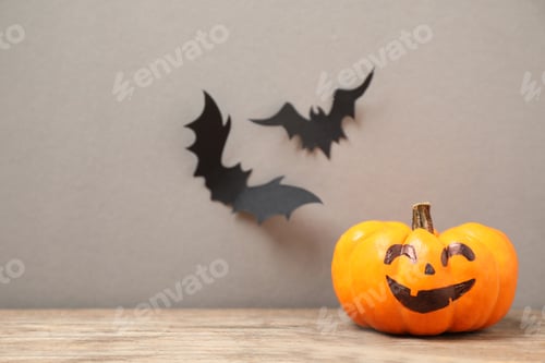 Preview: Pumpkin with scary face near decorative bats on grey background, space for text. Happy Halloween