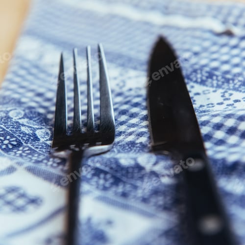 Preview: knife and fork at napkin on wooden background