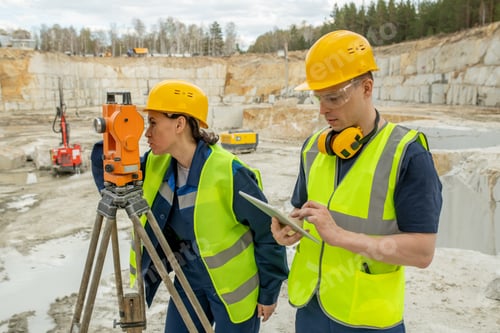 Preview: Female engineer using geodetic station by her colleague