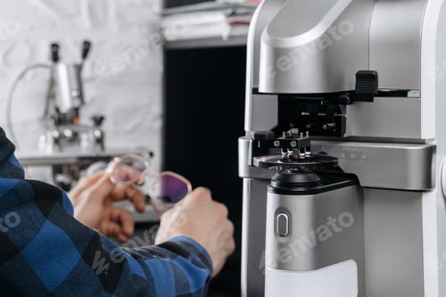 Preview: Optician's hands holding eyeglasses in professional workshop