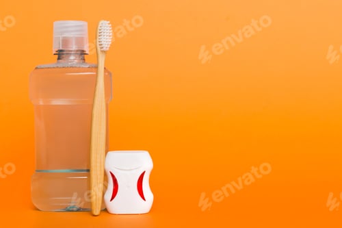 Preview: Mouthwash and other oral hygiene products on colored table top view with copy space