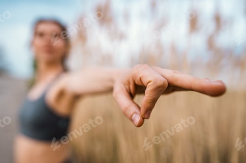 Preview: European woman doing yoga exercise on reed natural background. Concentrated girl training at summer