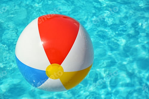Preview: Colorful beach ball floating in swimming pool on sunny day. Space for text