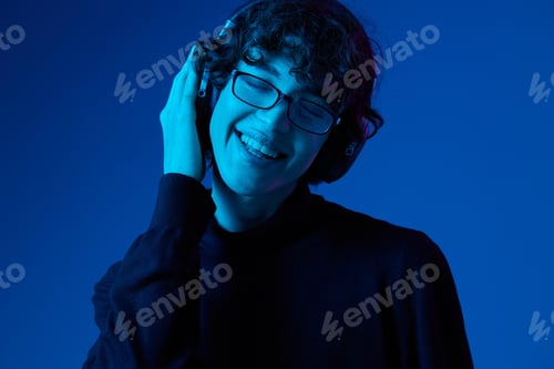 Preview: Teenage man wearing headphones listening to music and dancing and singing with glasses, hipster