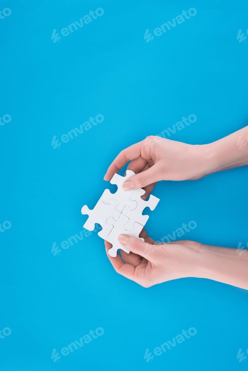 Preview: cropped image of businesswoman holding assembled puzzles isolated on blue, business concept