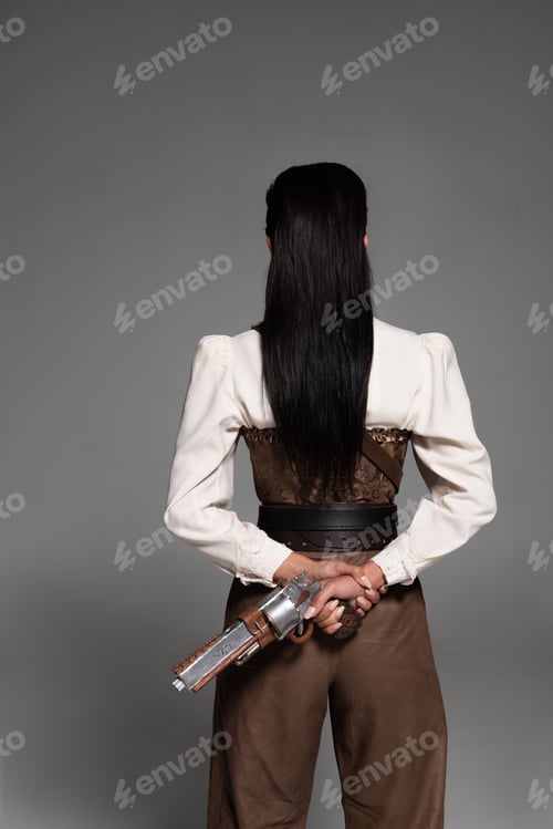 Preview: back view of steampunk woman holding vintage pistol on grey