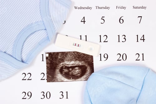 Preview: Pregnancy test, ultrasound scan of baby and clothing for newborn on calendar