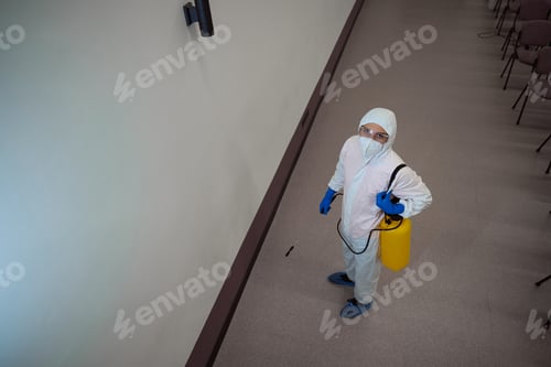 Preview: Certified janitor in protective suit preparing for disinfective fogging