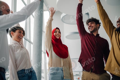 Preview: Happy multi ethnic business team celebrating success in modern office