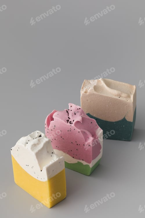 Preview: Pieces of different shapes and colors of handmade soap on a gray background. Natural cosmetics.