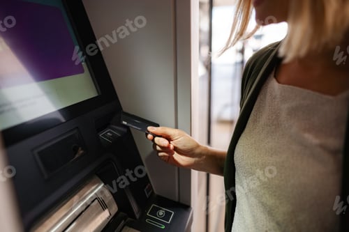 Preview: Woman inserting credit card into ATM for banking transaction