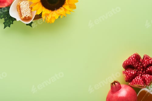 Preview: Rosh Hashanah. Ripe pomegranate, apple, honey and sunflower, yellow flowers on green background. com