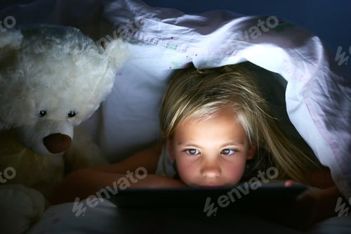 Preview: Shot of a little girl using a digital tablet under a blanket fort at home