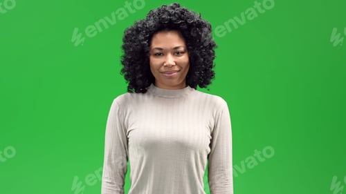 Preview: Young black African American female with a curly afro smiling on a green screen background