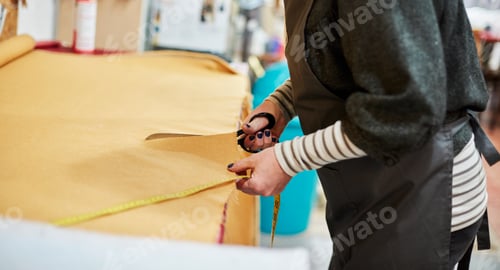 Preview: A woman cutting out yellow upholstery fabric on a workbench with a large pair of scissors.