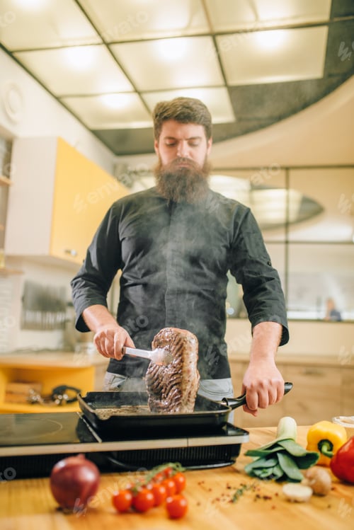 Preview: Male person cooking meat in a pan on the kitchen