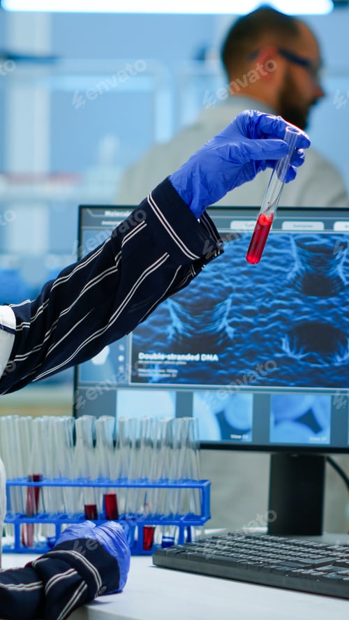 Preview: Scientist doctor looking at blood sample and writing on computer