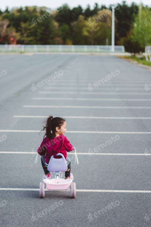 Preview: Diverse mixed race pre school age girl outdoors in nature enjoying weather and having fun on bike