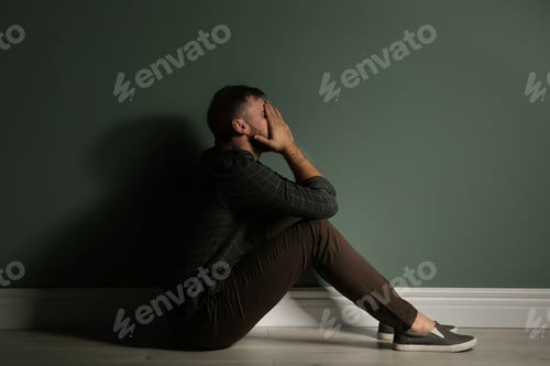 Preview: Depressed young man sitting on floor in darkness