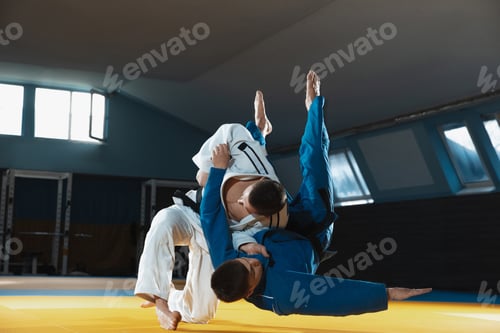 Preview: Two young judo fighters in kimono training martial arts in the gym with expression, in action and