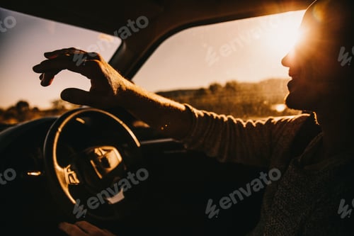 Preview: Young happy male adult driving car at sunset smiling