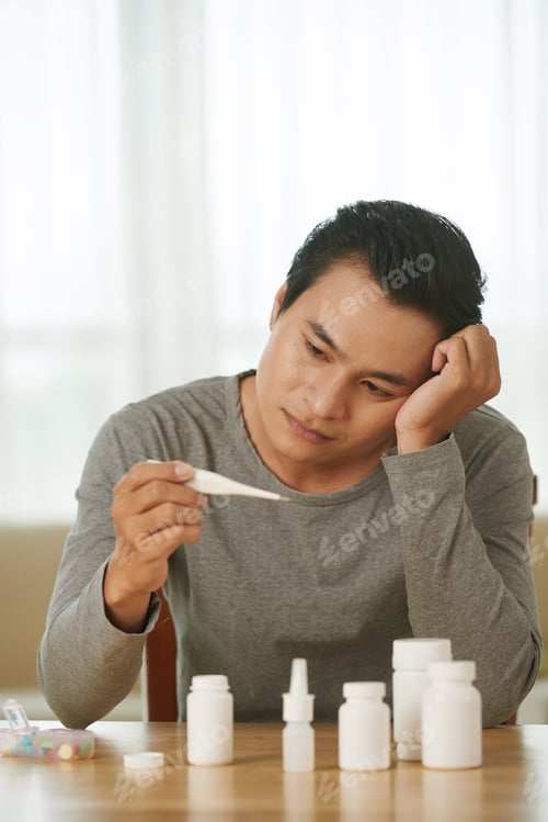 Preview: Man with Fever Holds Thermometer in Hand