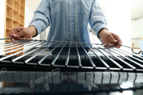 Preview: Female hands with a black modern oven