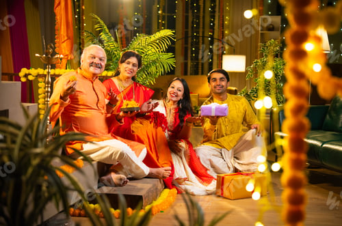 Preview: Joyful Indian family enjoying Diwali celebration together indoors with laddus, lights, and laught
