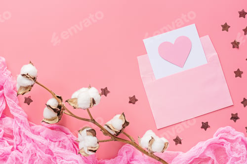 Preview: Flat lay of message with heart in envelope and cotton flower on pink background with copy space