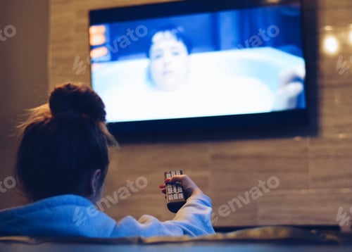 Preview: Young teenage girl is sitting on a couch watching TV